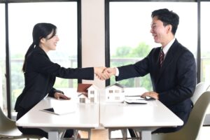 不動産業界への転職で内定を受け、担当者と握手する求職者のイメージ